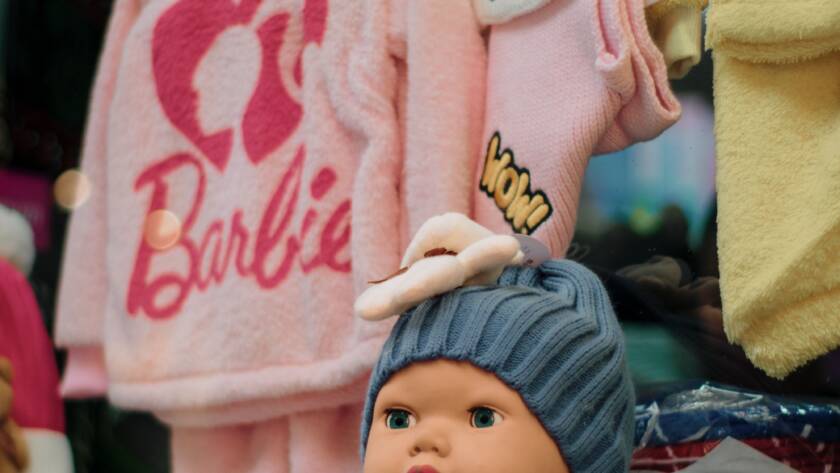 Pink girls' clothes and hats on display in a children's store, illustrating the pink tax