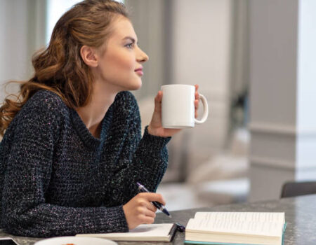Woman reflecting on money mindset and self-worth with journal and coffee - Accountant in Tasman