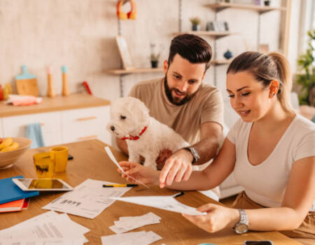 Couple sitting at a desk reviewing financial documents, reflecting on the emotional and mental load of being the financially capable person, as an Accountant in Motueka explores responsibilities in relationships or work.